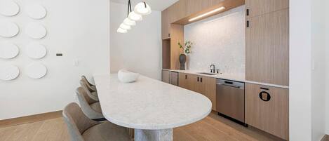 A modern kitchen with a marble countertop, wooden cabinets, and a built-in dishwasher.