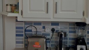 Una cocina con armarios blancos, un tostador, una licuadora y una tetera.