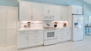 A modern kitchen with white cabinets, a stainless steel refrigerator, a microwave, and a stove. - Family Friendly Home in Naples, Near Beach, Heated Pool, Dog Friendly (Naples)