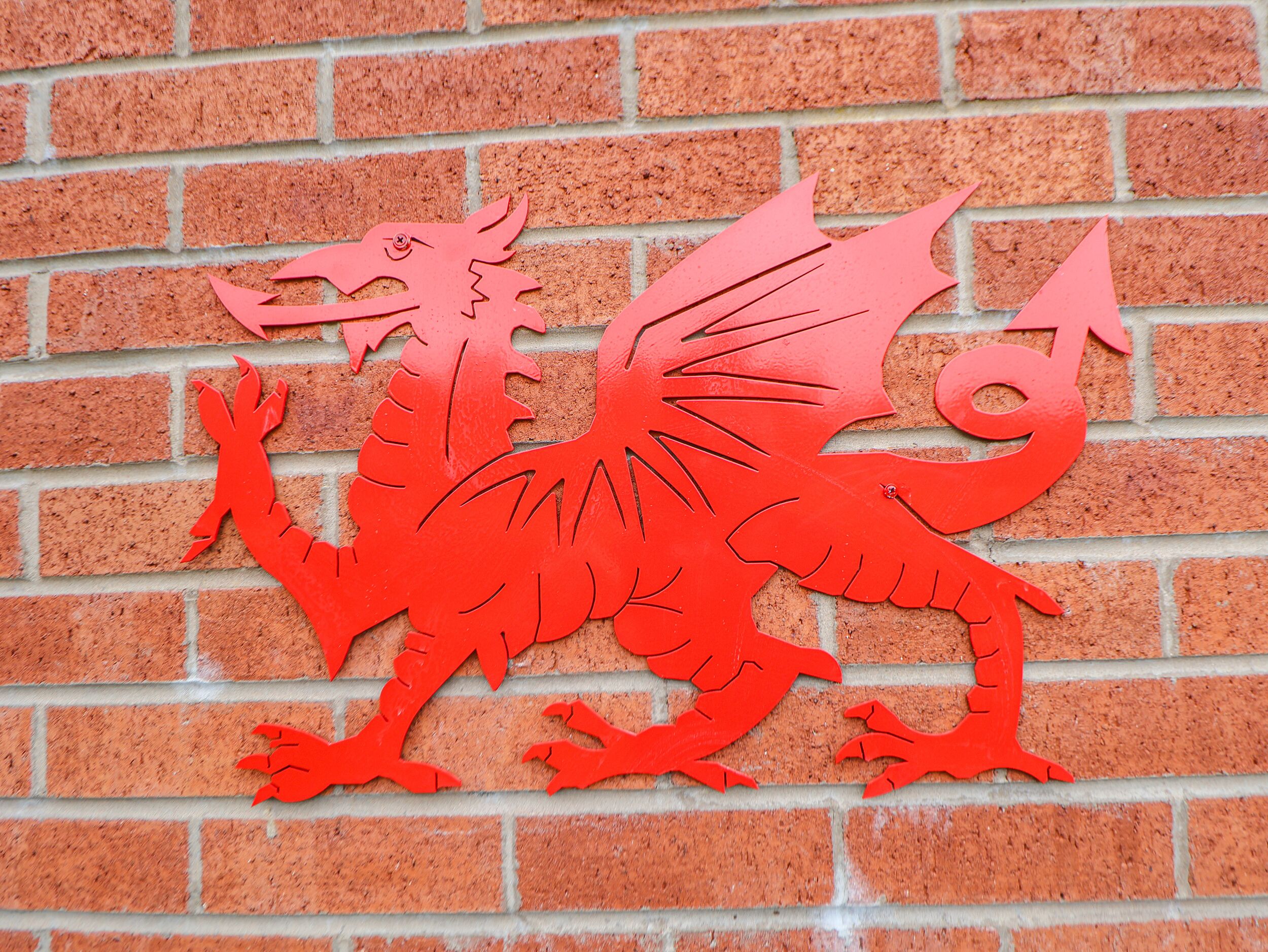 A red dragon cutout on a brick wall.