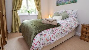 A bedroom with a bed, a nightstand, a window with curtains, a painting on the wall, and a wooden wardrobe. - 2 Mountain View (Wrexham)