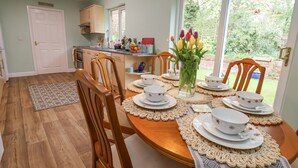 A dining area with a wooden table set for four, surrounded by chairs. - 2 Mountain View (Wrexham)