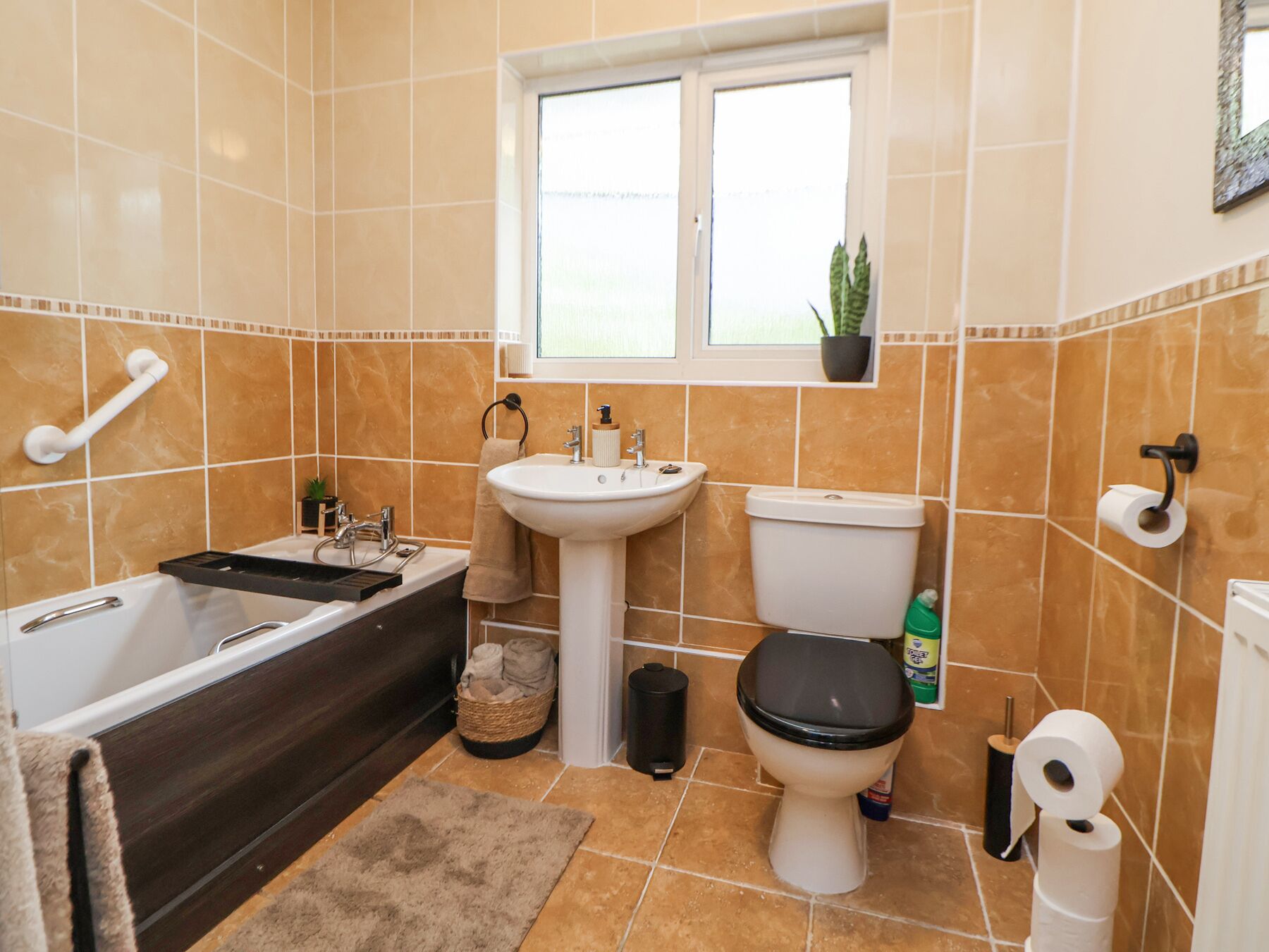 Ein Badezimmer mit Badewanne, Waschbecken, Toilette und einem Fenster.