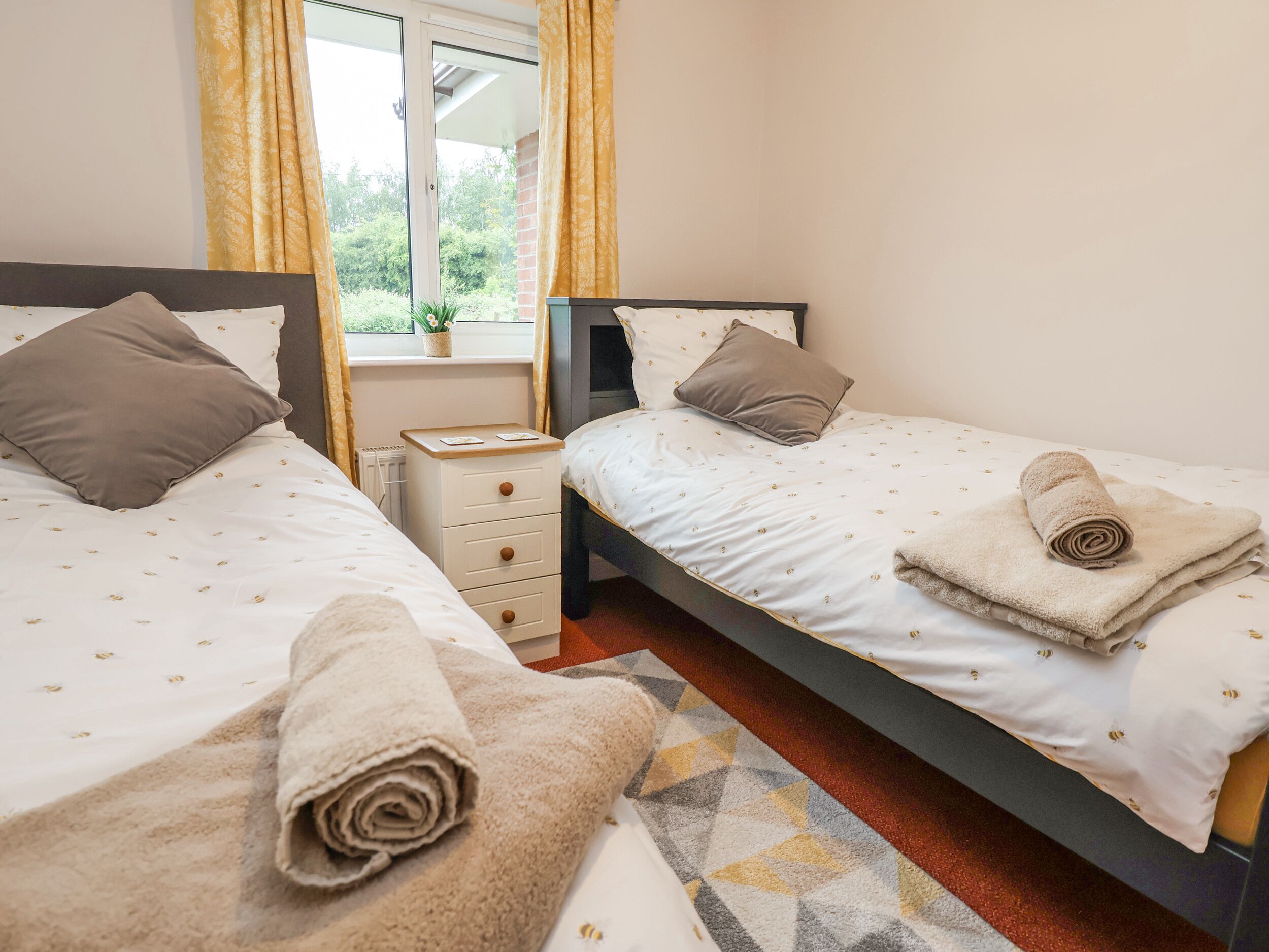 Une chambre avec deux lits, une table de chevet et une fenêtre avec des rideaux.