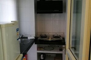 Une cuisine de taille réduite équipée d’un réfrigérateur, d’un évier, d’une cuisinière et d’une fenêtre.