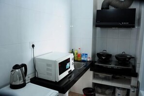 A kitchen with a microwave, stove, sink, and various kitchen items. - Shier Weidi Business Apartment (Shenzhen KK100) (Shenzhen)