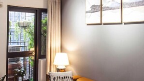 Ein Zimmer mit einem braunen Ledersofa, einer Lampe und einem Fenster mit Vorhängen.