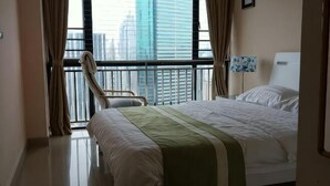 Ein Hotelzimmer mit Bett, Sessel, Fenster mit Stadtblick und Nachttisch mit Lampe.