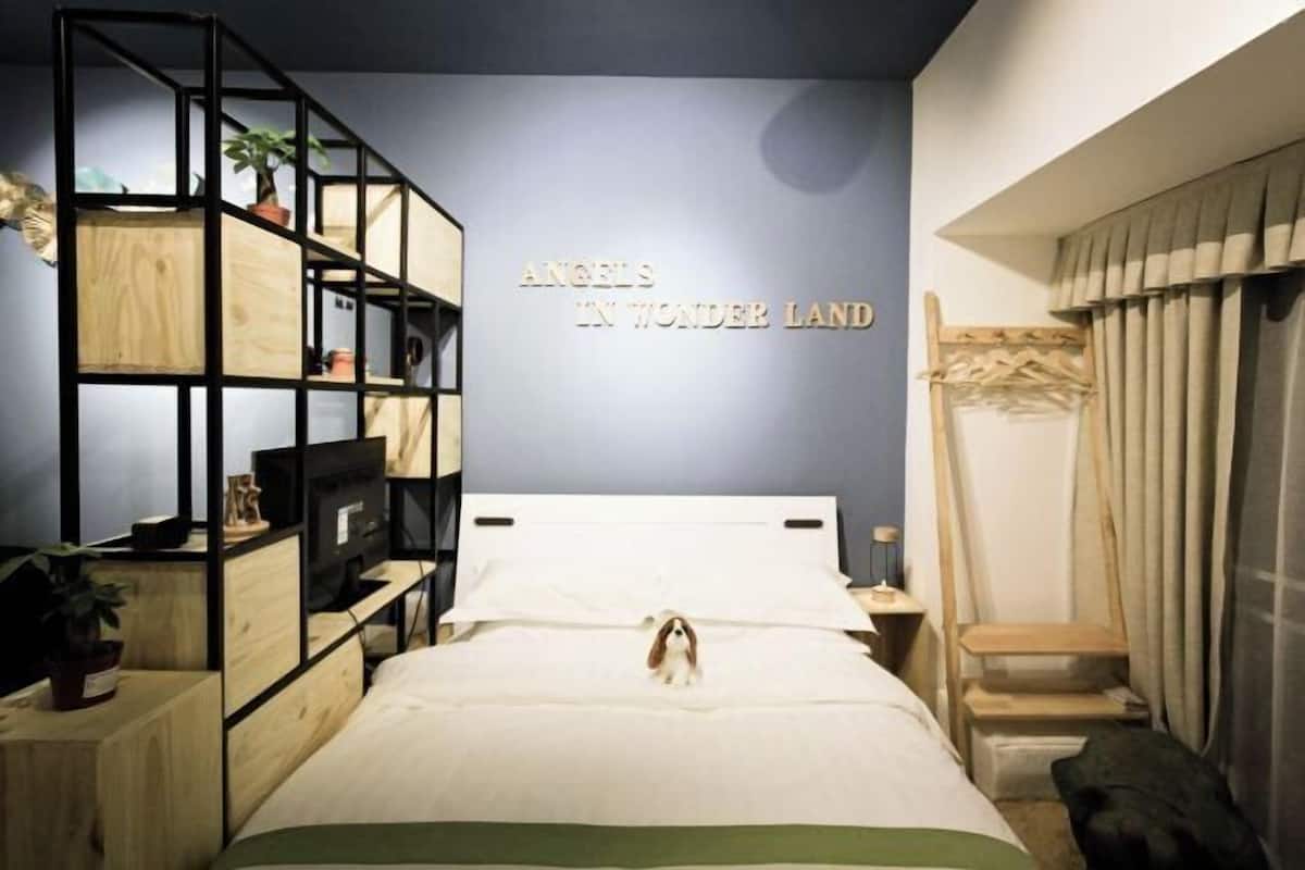 Une chambre à coucher avec un lit, une biblioth èque, un téléviseur et un mur sur lequel est écrit : « ANGELS IN WONDER LAND ».