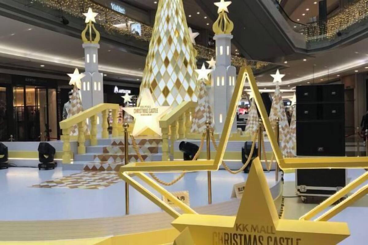 Une décoration sur le thème de Noël, avec des structures dorées et des décorations en forme d’étoiles, dans un centre commercial.