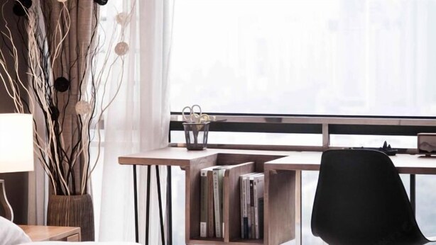 Ein Schlafzimmer mit Bett, Schreibtisch mit Stuhl, Bücherregal und Fenster mit Ausblick.