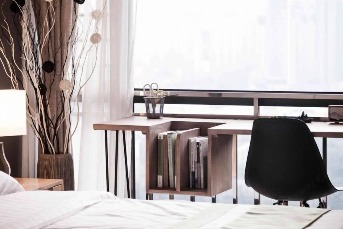Une chambre à coucher comprenant un lit, un bureau avec une chaise, une bibliothèque et une fenêtre donnant sur un paysage agréable.