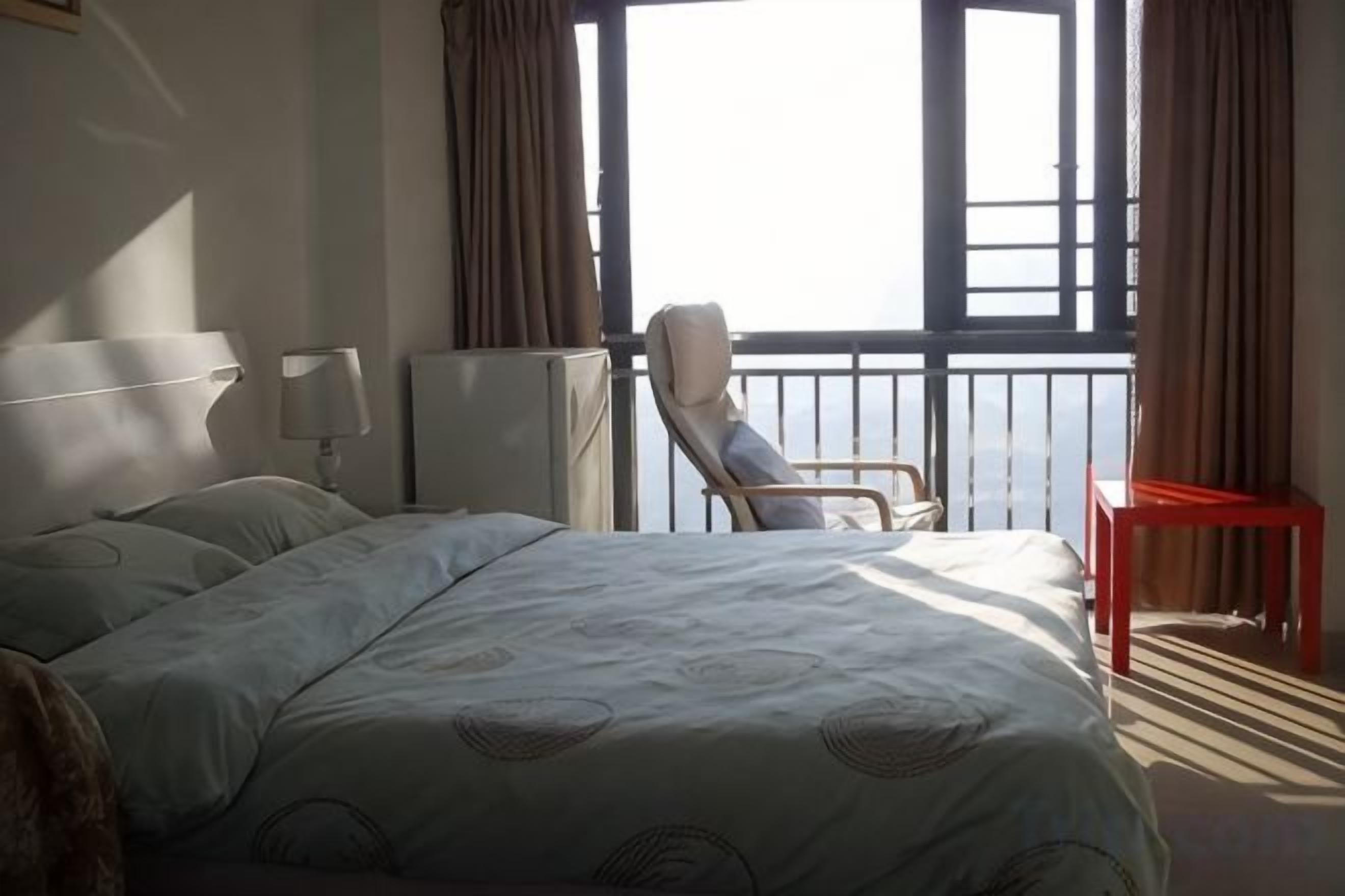 Une chambre d’hôtel avec un lit, une chaise, une petite table et une fenêtre donnant sur un paysage agréable.