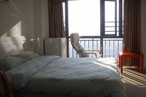 Une chambre d’hôtel avec un lit, une chaise, une petite table et une fenêtre donnant sur un paysage agréable.