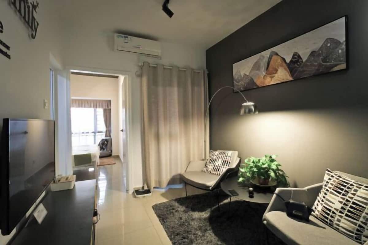 Un salon moderne avec un téléviseur à écran plat, un canapé, un fauteuil et un tableau accroché au mur.