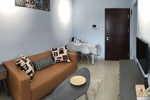 A living room with a sofa, a coffee table, a TV, and a dining area with chairs and a table. - Shier Weidi Business Apartment (Shenzhen KK100) (Shenzhen)
