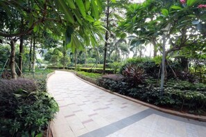 A paved pathway in a landscaped area with various plants and trees. - Shier Weidi Business Apartment (Shenzhen KK100) (Shenzhen)