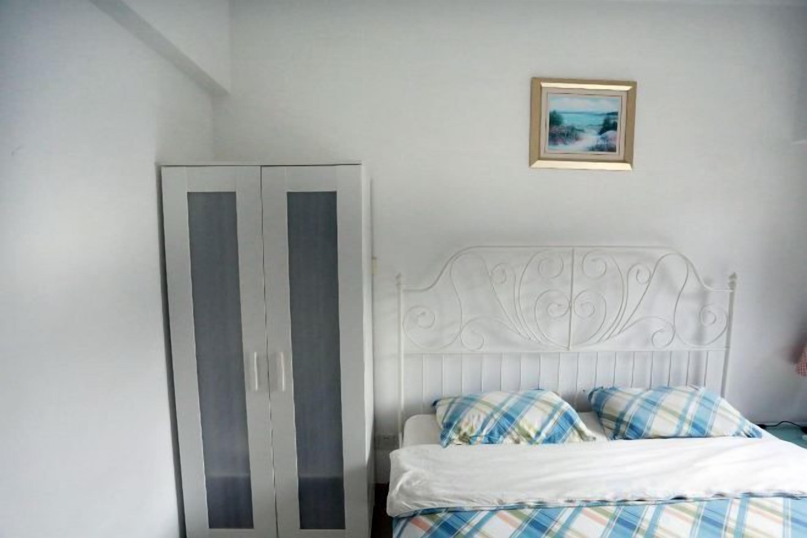 Une chambre à coucher avec un lit, une armoire et un tableau encadré accroché au mur.