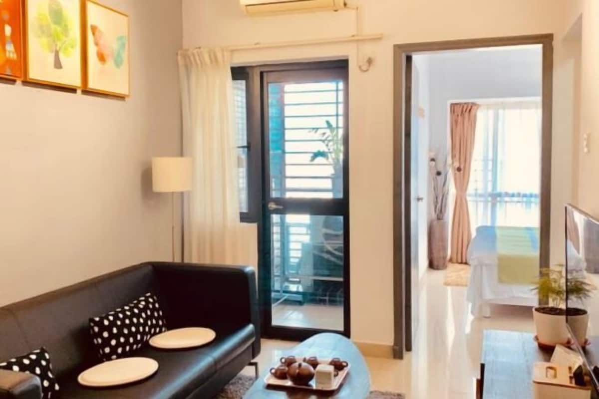 Un salon moderne avec un canapé, une table basse et une porte-fenêtre coulissante donnant sur un balcon.