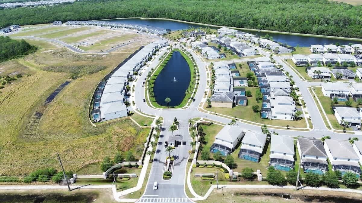 Luchtbeeld van een woongebied met een centraal gelegen meer, omringd door huizen en een weg.