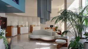 Een moderne lobby met een gebogen bank, een receptiebalie en plantenpotten.