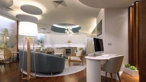 Een modern interieur met een gebogen blauwe bank, een ronde witte tafel met een computer, en een houten stoel.