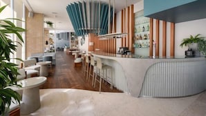 Een moderne bar met een gebogen toonbank, barstoelen en een opvallend plafondontwerp.