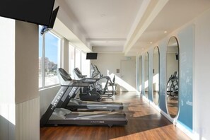Ein Fitnessstudio mit Laufbändern, Crosstrainern und Spiegeln an den Wänden.