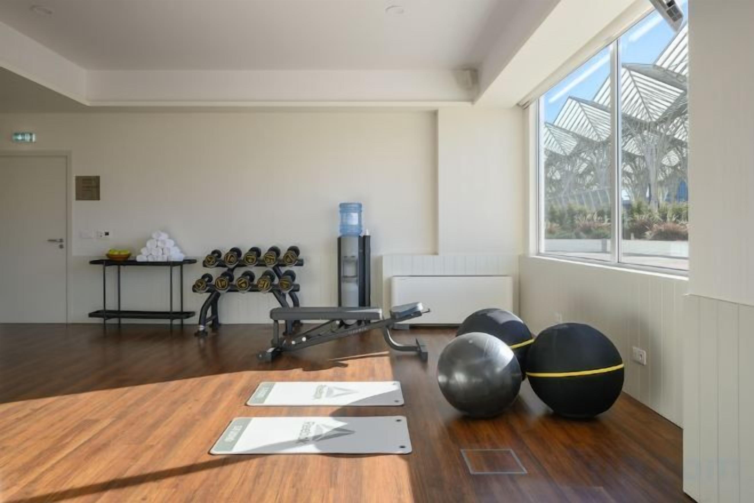 Une salle de sport équipée de matériel d’exercice, dotée d’un distributeur d’eau et offrant une vue sur l’extérieur.