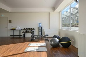Uma academia com equipamentos de ginástica, bebedouro e vista para o exterior.