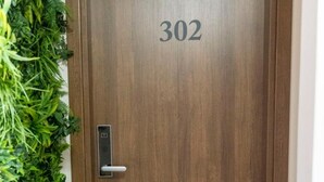 Eine Holztür mit der Nummer 302, einem modernen Türgriff und einer grünen Pflanzenwand links.