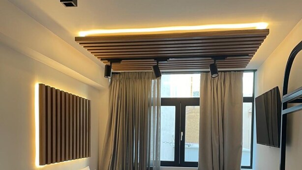 Ein modernes Schlafzimmer mit Bett, Vorhängen, einem Fernseher und einer Deckenleuchte.