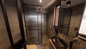 Une salle de bain moderne avec un grand miroir, un lavabo noir et des toilettes.