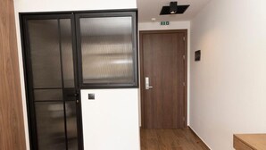 Un couloir doté d’un plancher en bois, d’un mur blanc et d’une porte à cadre noir.