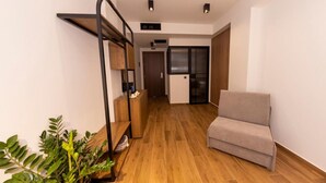 Un salon moderne avec un canapé, un plancher en bois, un banc intégré et une plante en pot.