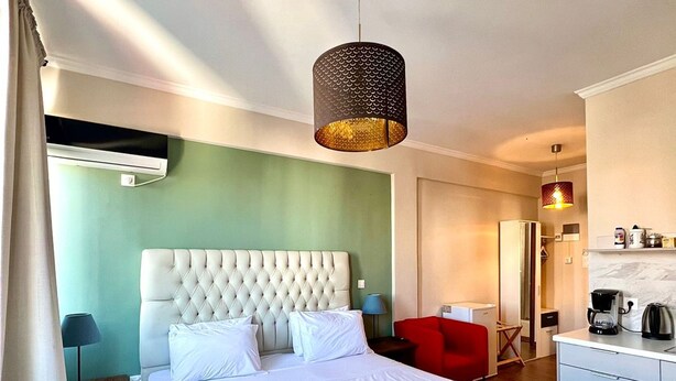 Ein Hotelzimmer mit einem großen Bett, einem Schreibtisch, einem Stuhl und einer Küchenzeile.