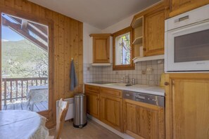 Eine Küche mit Holzausstattung, einem Spülbecken und einem Fenster mit Blick auf einen Balkon.