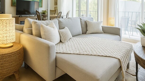 Ein modernes Schlafzimmer mit einem großen Bett, einem Fernseher und einem Balkon mit Gartenmöbeln.