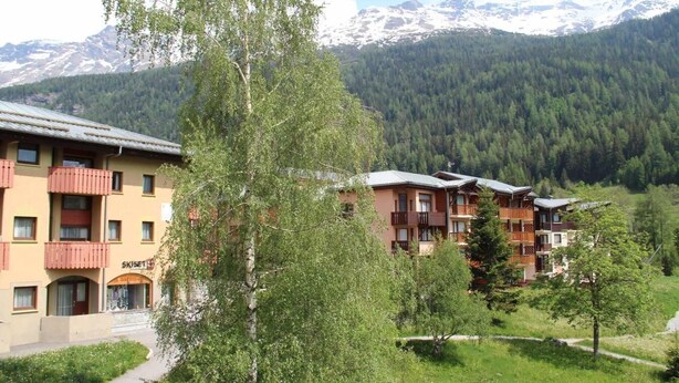 Een hotel met meerdere verdiepingen, balkons en uitzicht op besneeuwde bergen.