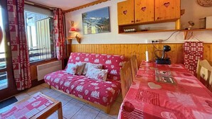 Une pièce chaleureuse avec un lit en bois, une table à manger et un coin cuisine doté de placards en bois.