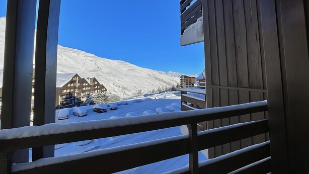 Un balcon avec vue sur une montagne enneigée et des bâtiments.