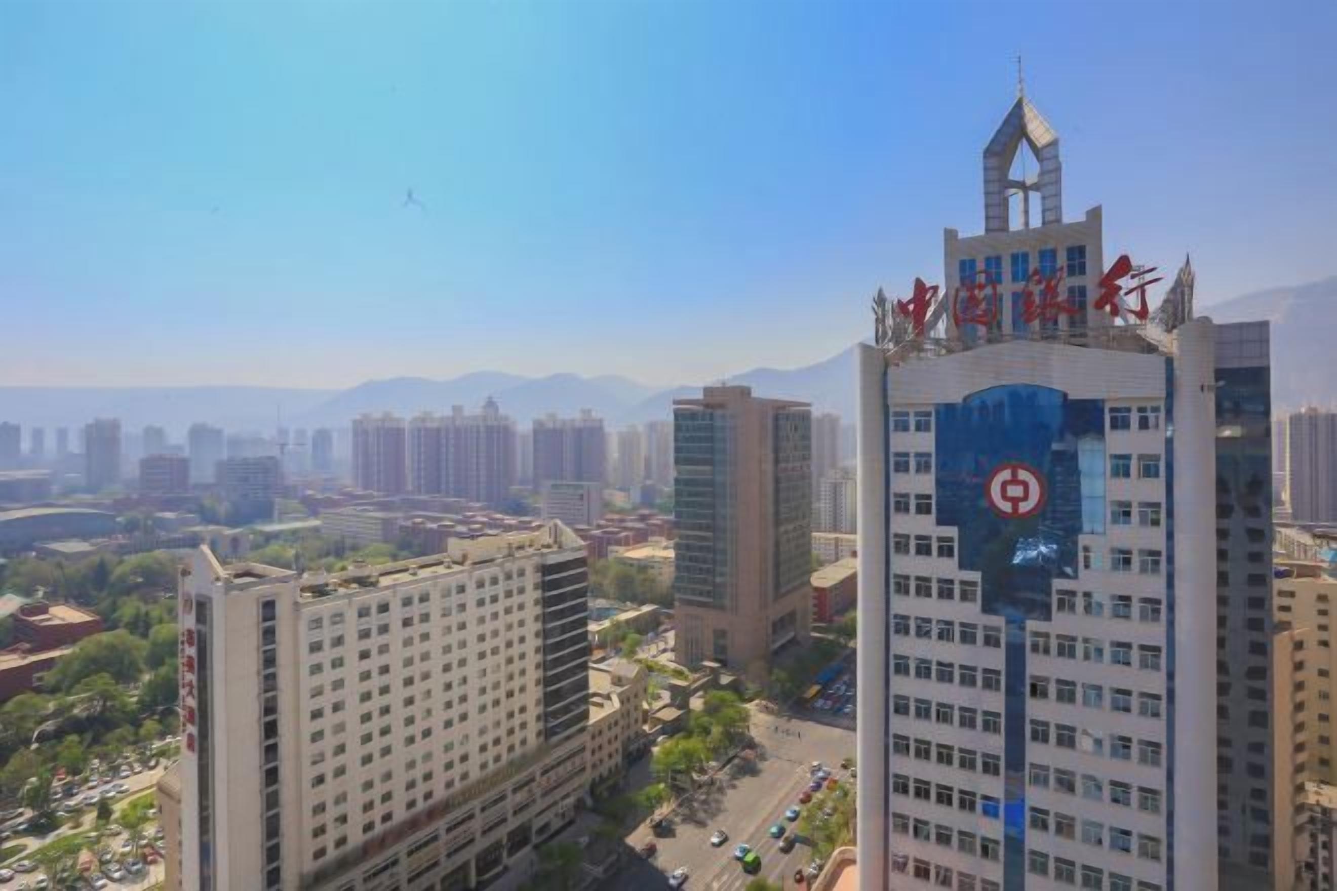 A high-rise building with multiple floors, a prominent red logo on the top, and a clear view of the surrounding cityscape.