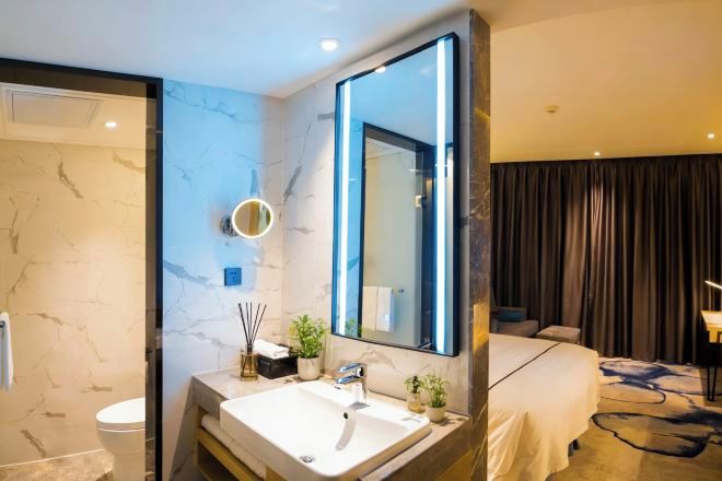 A modern bathroom with a large mirror, a sink, and a toilet.