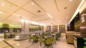 Un hall d’entrée spacieux avec un sol en marbre, des fauteuils verts, un comptoir d’accueil et un espace détente avec des canapés.