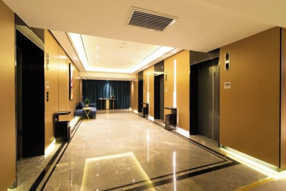 A hotel lobby with a marble floor, elevators, a sofa, and a blue curtain.