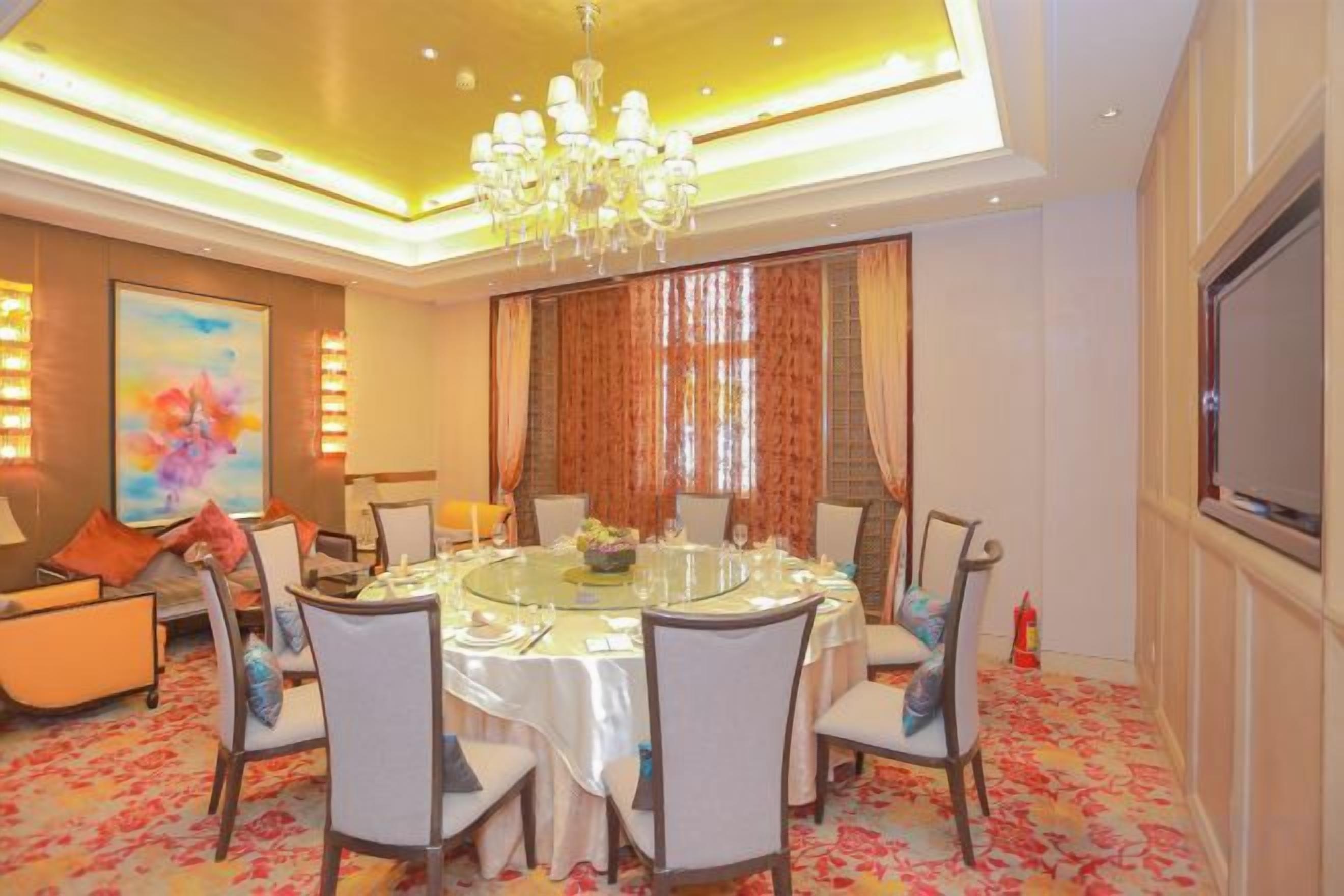 A dining area with a round table, chairs, and a chandelier.