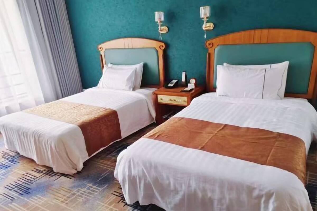 Two single beds with wooden headboards, white bedding, and a nightstand with a phone and lamp.