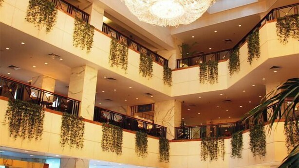 Un atrium à plusieurs niveaux, agrémenté de plantes suspendues, de colonnes en marbre et d’un grand lustre.