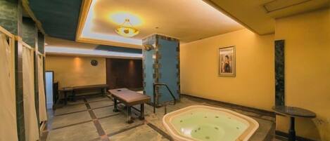 A room with a large bathtub, a bench, and a table.