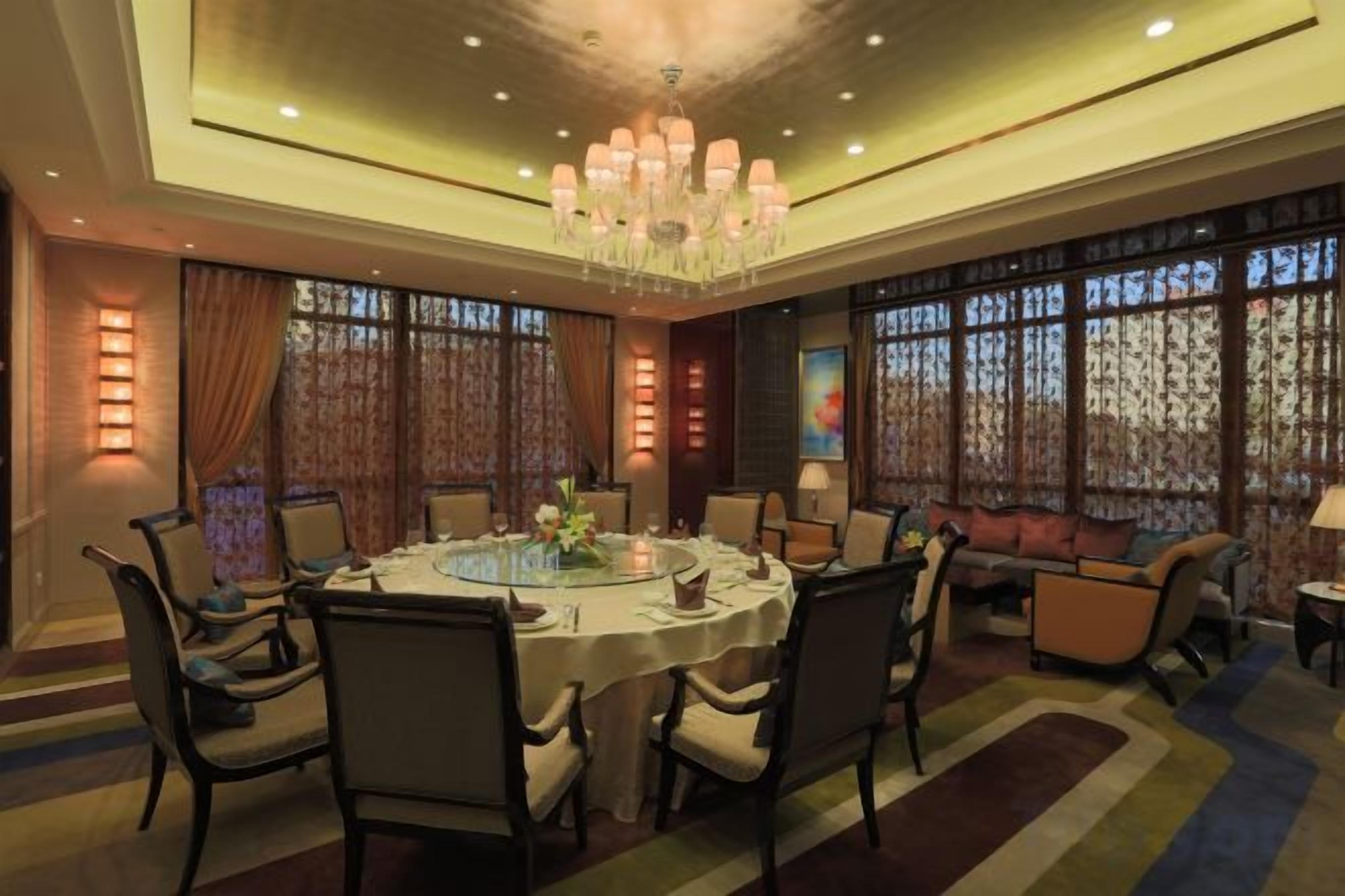 A dining area with a round table, chairs, and a chandelier.